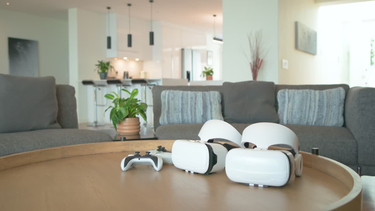 Camera pushing in, panning right, highlighting VR headsets and controller on table in living room