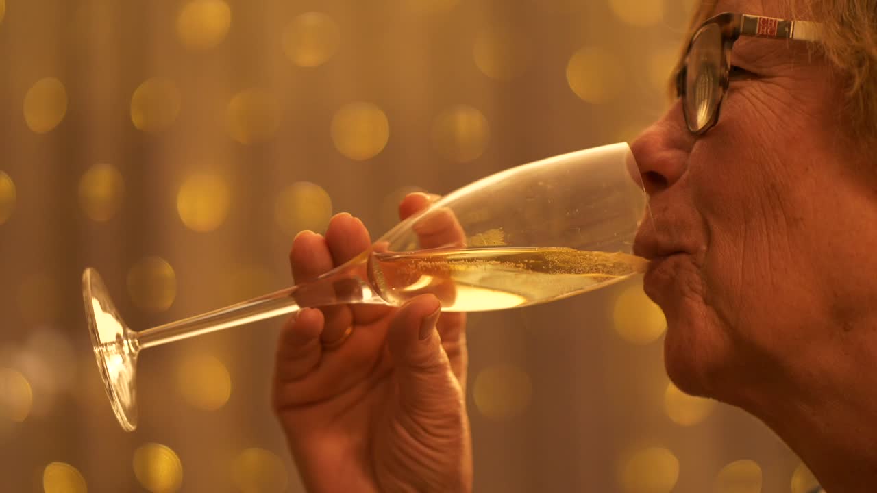 안경을 쓴 노인 여성은 플루트, 근접 촬영에서 샴페인을 마신다