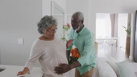 a senior african american man offering flowers to his wife