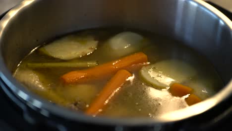 healthy chicken soup in pot cooking and bubbling with vegetables floating