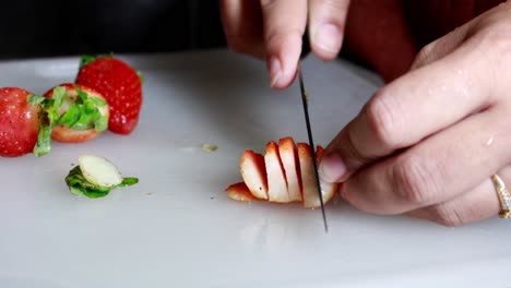mujeres cortando a mano fresas rojas