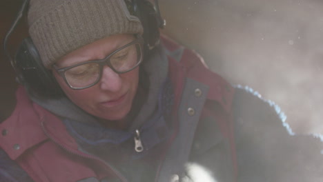 slomo frontal de primer plano de una mujer con gafas en ppe cortando metal, disparo retroiluminado