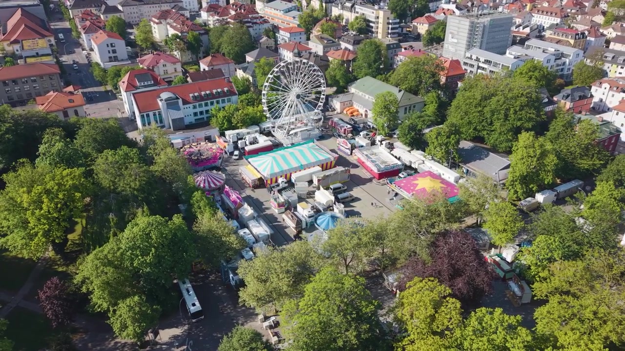Umlaufende Drohnenaufnahme des Stadtzentrums von Kempten Allgäu in Deutschland, mit Riesenrad, historischen Dächern, üppigem Grün und lebendiger bayerischer Stadtlandschaft an einem sonnigen Tag in UHD.