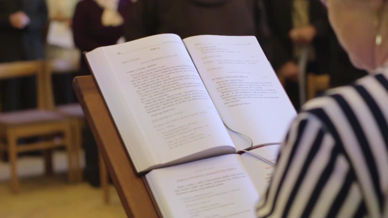 la escritura está siendo leída en voz alta por una anciana en la iglesia