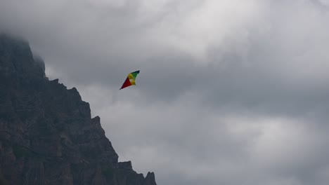 una cometa multicolor gira en un cielo nublado y ventoso sobre los alpes suizos, obwalden