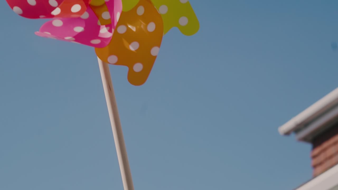 cámara panorámica de la mano de un niño a un brillante hilador de molino de viento feliz