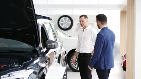 un cliente masculino eligiendo un coche en el concesionario con la ayuda de un vendedor de automóviles