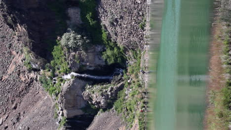 Vertical-format:-Hikers-at-base-of-Ancient-Lakes-waterfall-in-canyon