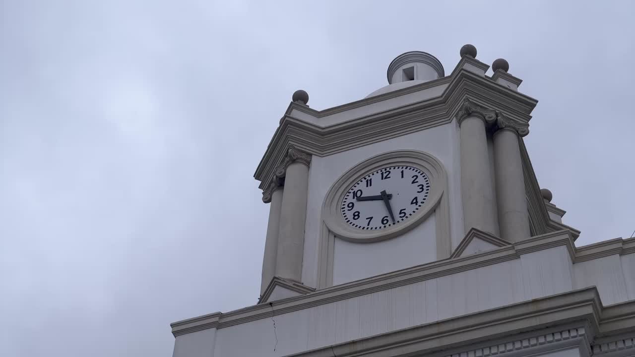 Time lapse of town hall clock with sky clouds moving fast in the background