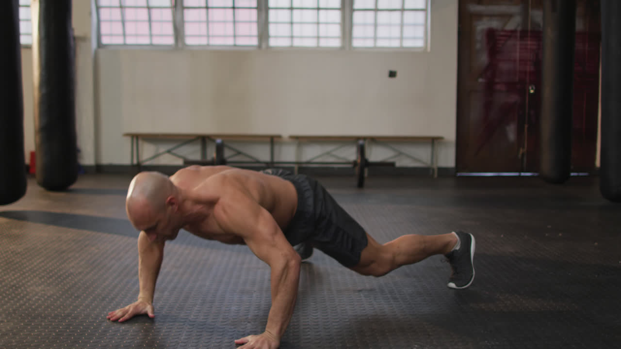 hombre calvo caucásico musculoso sin camisa haciendo ejercicios, haciendo flexiones