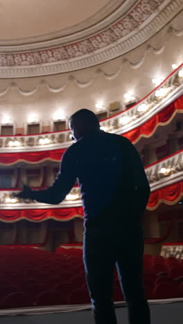 man on stage on classical theater hall background. rehearsal before the performance. actor is talking to the empty auditorium. view from scene. vertical video