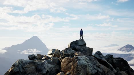 adventurous male hiker standing on rocky cliff surrounded by mountains