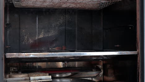 person removing freshly smoked sausage from electric smoker, close up