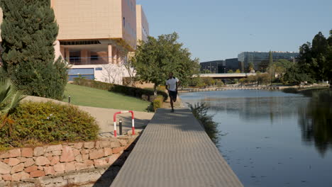 young black runner man jogging and training outdoors towards the camera