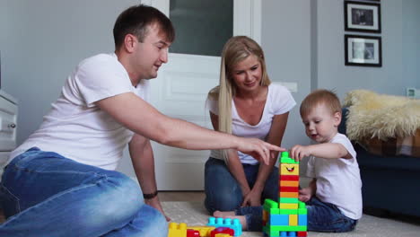 happy family dad mom and baby 2 years playing lego in their bright living room. slow-motion shooting happy family