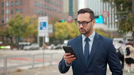 businessman manager reading email on phone in large city downtown area with traffic in background