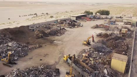 Fly-towards-scrap-yard-with-excavators-and-dump-trucks