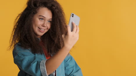Caucasian-curly-haired-woman-taking-selfies-on-smartphone.