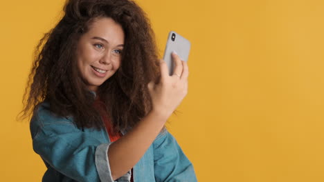 caucasian curly haired woman taking selfies on smartphone.