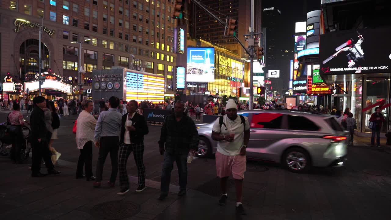Pedestrians move quickly through the area, some stopping to shop or dine, while others join the throng crossing the street at the busiest intersection of Times Square