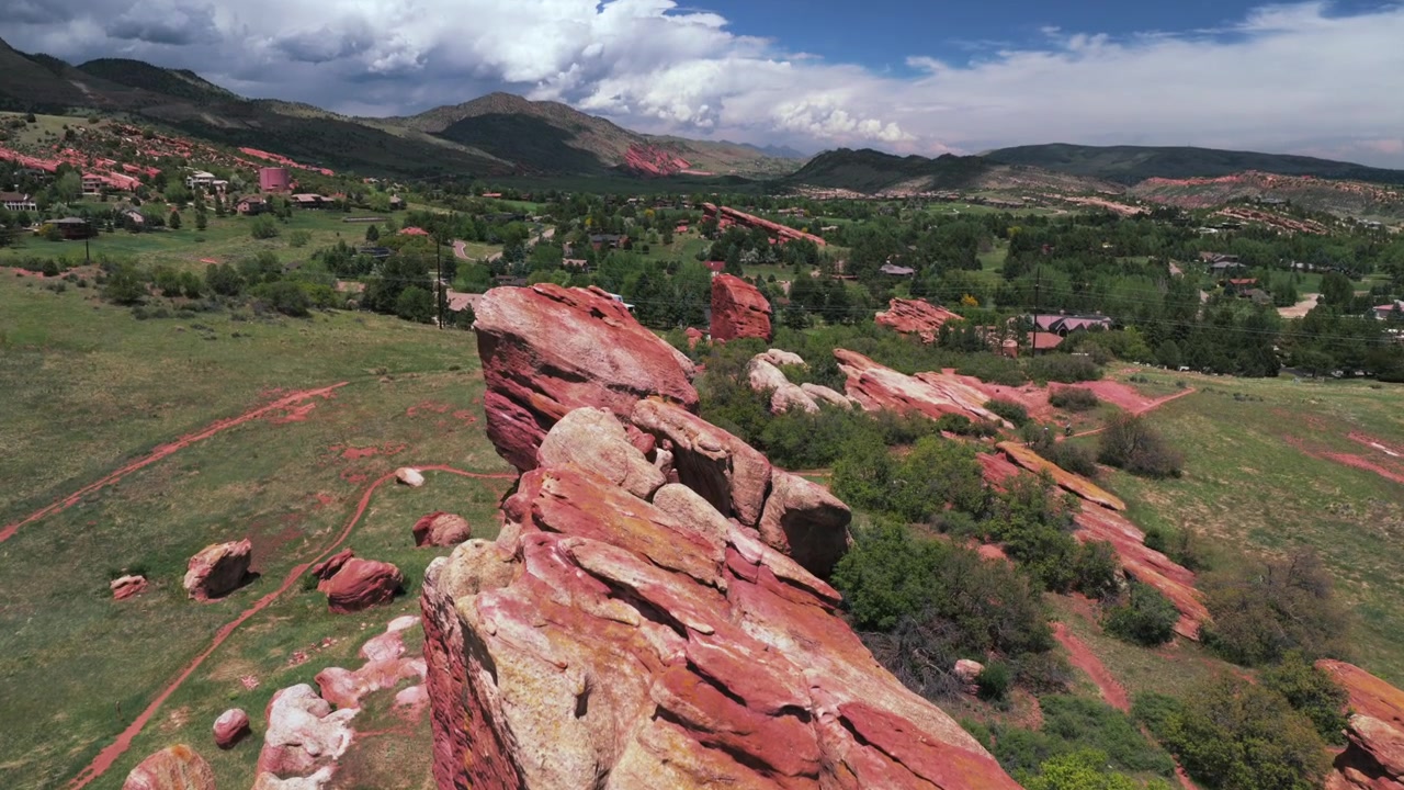 Trilhas de caminhada de Red Rocks, casas do bairro Ken Caryl Valley Ranch, North Valley Meadow Ranch, Front Range, Denver, Colorado. Vista aérea de drone dos sopés das Montanhas Rochosas em uma manhã de verão nublada, com panorâmica para baixo e para frente.