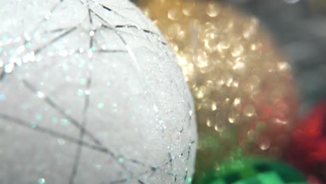 decoración de navidad, coloridos adornos de cristal oro, azul, verde, rojo y gran bola blanca, año nuevo decorado, luces brillantes, macro de primer plano inclinado hasta video 4k, hermosa profundidad de campo, luz bokeh