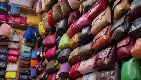 a variety of colorful leather bags stacked together inside a moroccan tannery