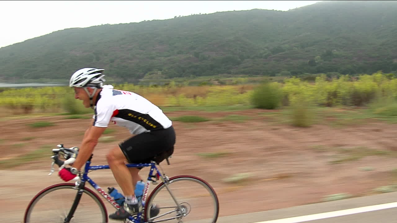 un ciclista sonríe mientras pedalea por una carretera en una zona rural