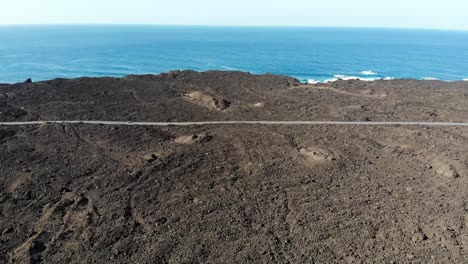Flug-über-Die-Lava,-Der-Sich-Einer-Straße-In-Der-Nähe-Des-Meeres-Auf-Der-Insel-Lanzarote-Nähert