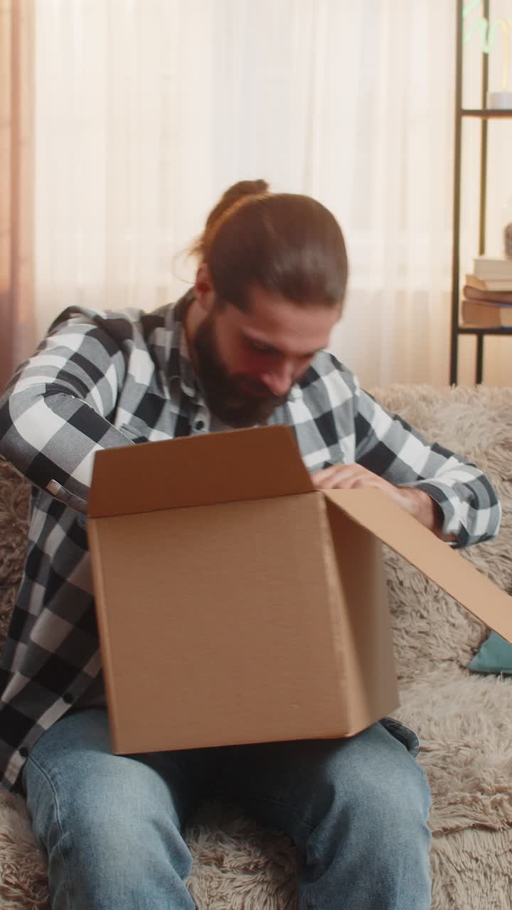 joven recibe la entrega en casa sofá desembalaje felicidad rápida gran revelar amigable onda pov