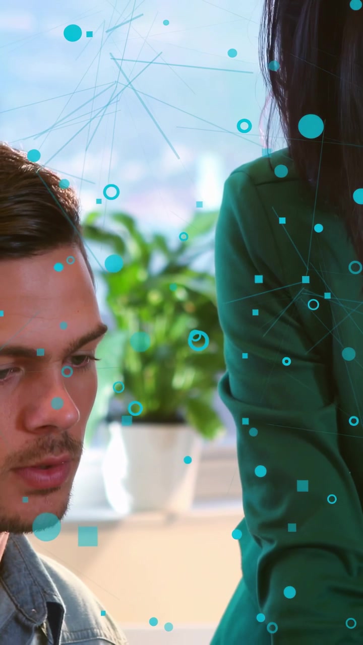 Vertical video: Business woman leaning and placing hand on laptop, man watching turquoise shapes