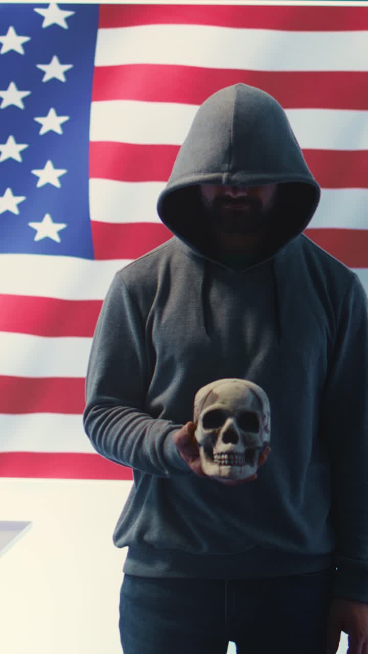 Figura incappucciata che tiene in mano un teschio di fronte a una bandiera americana