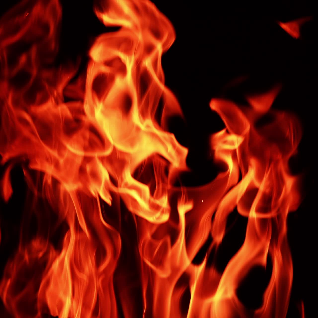 Tongues of flame burning at night. Isolated fire swaying in the wind in darkness