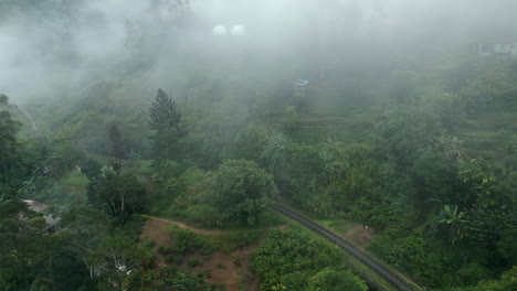 establishing aerial drone shot of hills and train track in ella on misty morning in sri lanka