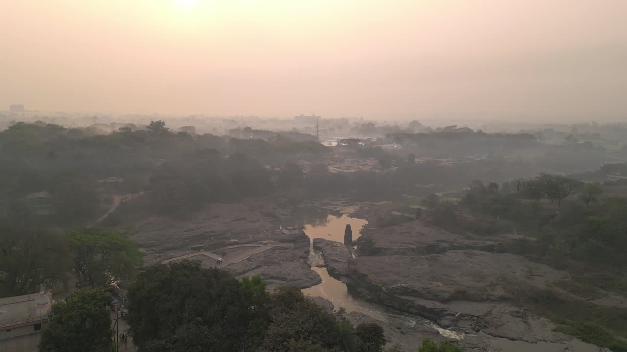 Veduta aerea di Nashik la sera, con la luce solare dorata che si riflette sul fiume Godavari, le strade della città che si snodano sotto, le colline che incorniciano lo skyline, catturando il fascino sereno ma vivace della riva del fiume urbano.
