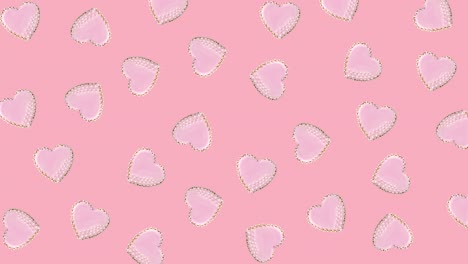 heart shaped cookies decorated with pink glaze wiggle on a pastel background