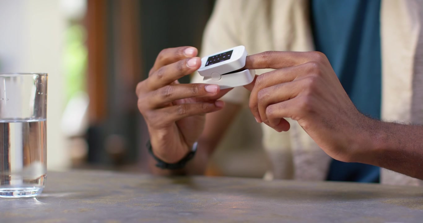 Man reaching to pick up white clip device, opening, inserting finger, adjusting, measuring on table