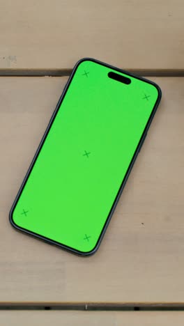 smartphone with green screen on wooden surface