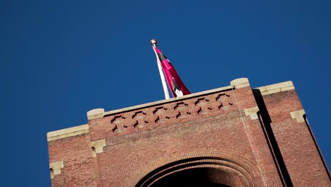 Drehpfanne-über-Altem-Rotem-Backsteingebäude-In-Amsterdam-Mit-Wehender-Stadtflagge-An-Der-Spitze