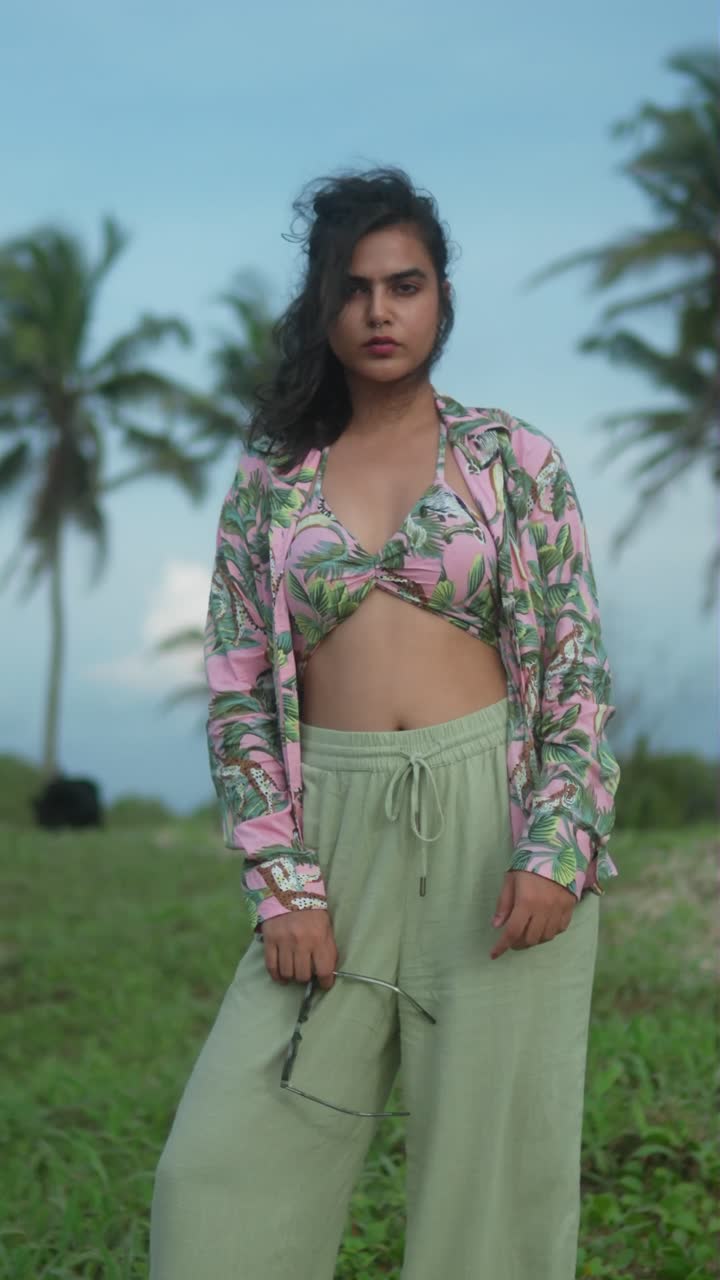 Bela Mulher em Traje Tropical Posando na Praia ao Pôr do Sol