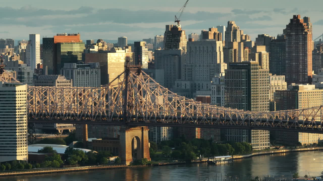 Aerial view of the Queensboro Bridge at sunrise. Shot along the East River with Roosevelt Island and Manhattan in the background