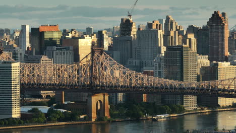 aerial view of the queensboro bridge at sunrise. shot along the east river with roosevelt island and manhattan in the background