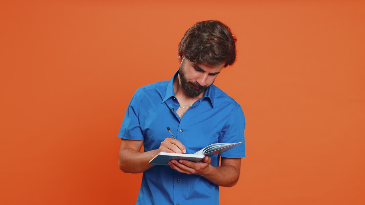 Thoughtful arabian man making notes, writing down thoughts with pen into notepad notebook, good idea