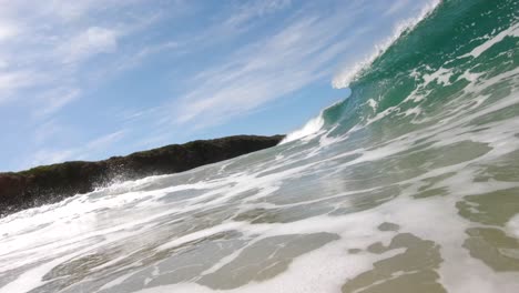 una toma en cámara lenta del agua de una ola que se precipita perfectamente en un día soleado azul