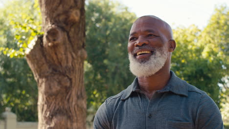 portrait of smiling senior man standing outdoors in garden park or countryside