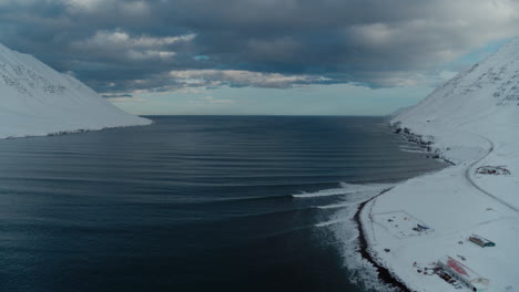 snowy mountains surrounding a frozen fjord in iceland during winter shot from a drone