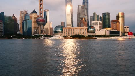 shanghai skyline viewed from bund, skyscrapers and landmarks with sunset light reflections on the ripples of huangpu river, loop able 4k b roll footage.