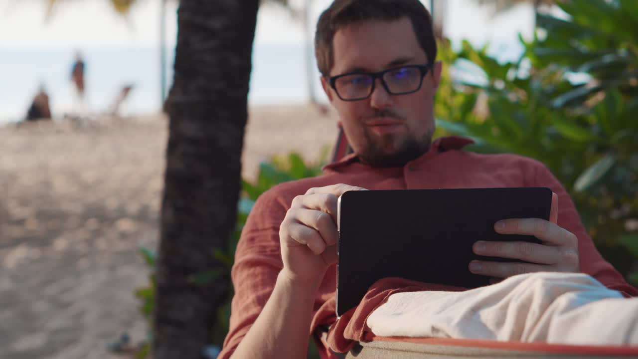 hombre relajándose en la playa, leyendo la tableta