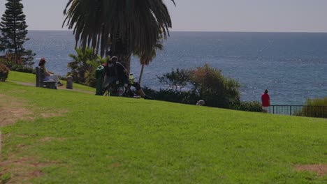 people sitting and enjoying the scenic ocean view, at a hillside park, in laguna beach california