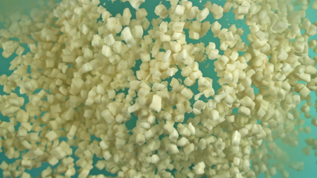 Piccoli cubetti di cibo tagliati a dadini che galleggiano in un liquido blu.